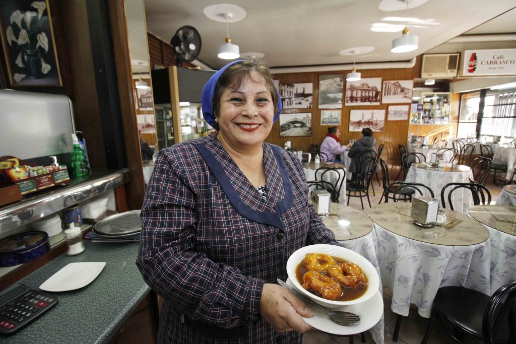 Trabajadora al interior de Café Carrasco con un plato de picarones.